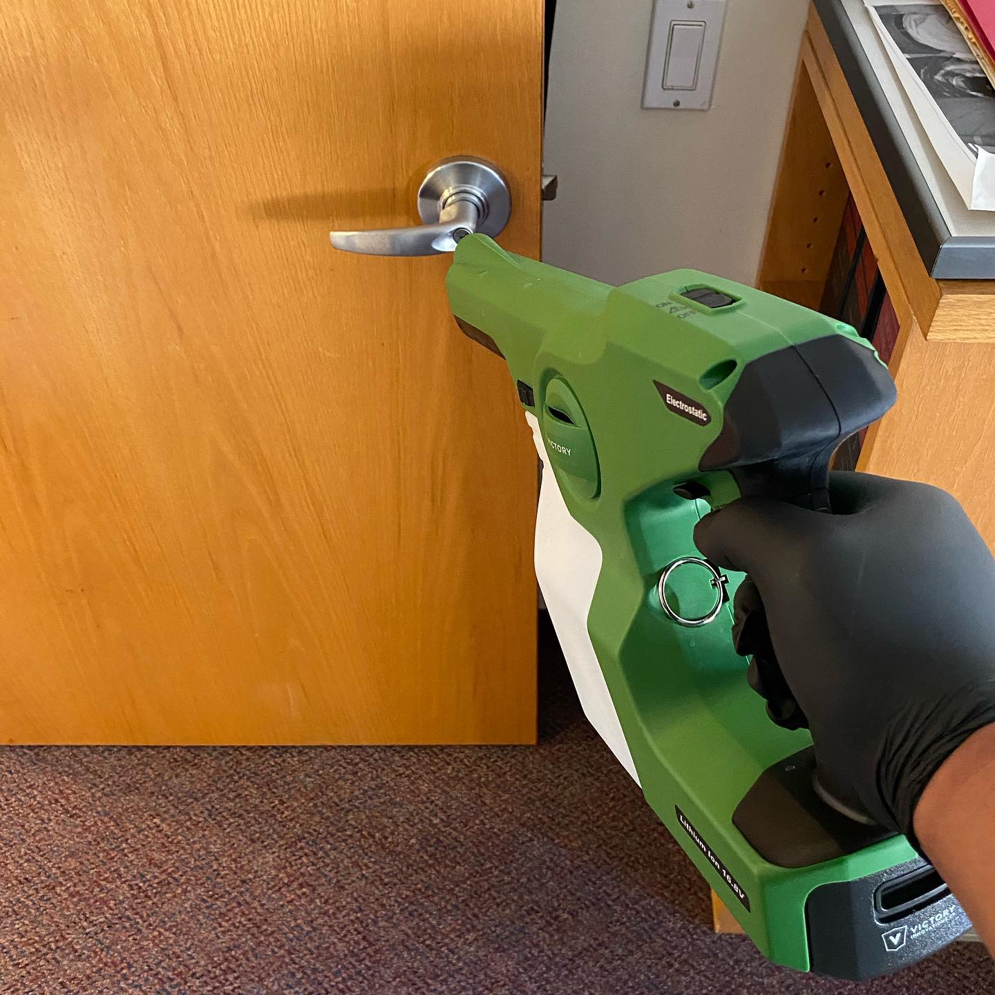 Disinfecting doors NYC office with electrostatic sprayer.